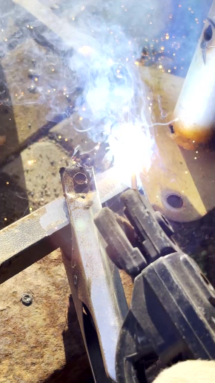 Vertical POV. Stick welding to connect pieces of metal together with blue sparks