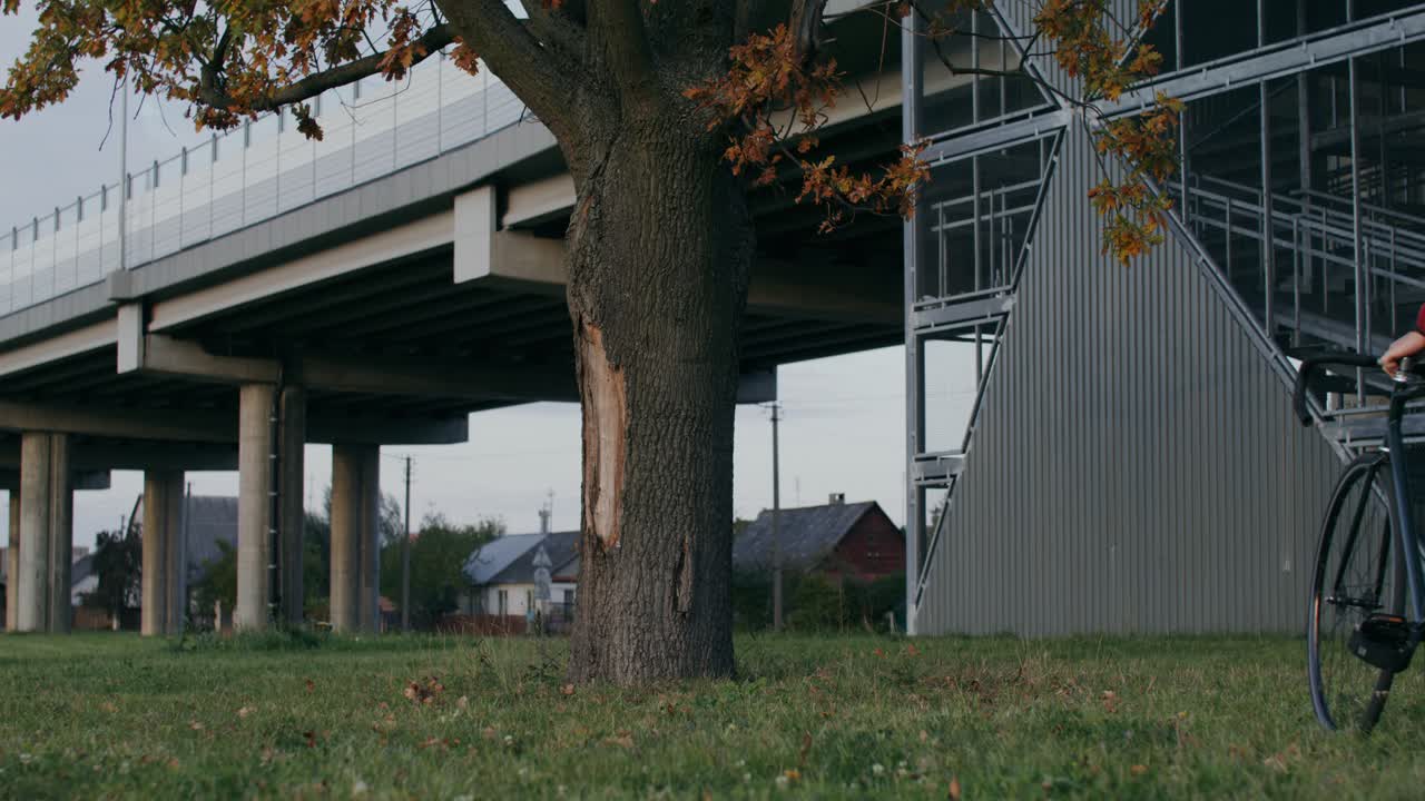 ciclista urbano descansando bajo un paso elevado.