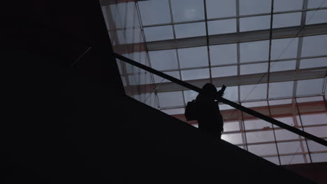 a silhouette of a man moving down on an escalator