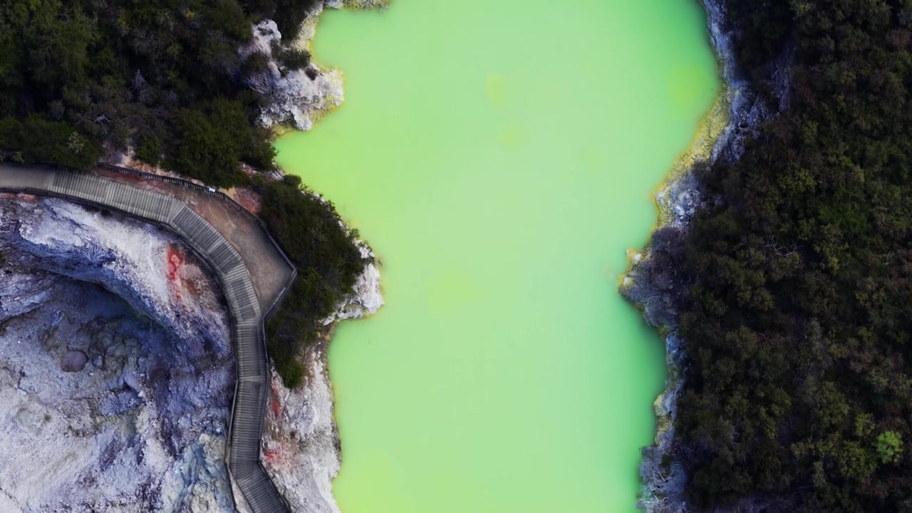Rotorua, Bay of Plenty, Uusi-Seelanti, ilmakuva smaragdinvihreästä geotermisestä järvestä, jossa on kävelysilta, vulkaanista maastoa ja alkuperäismetsää