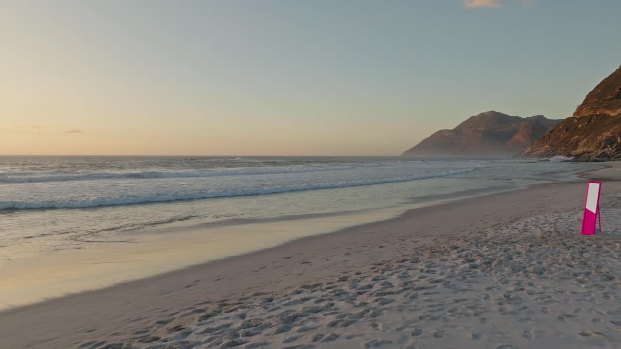 Drone shot of a pink mirror placed on the beautiful beach of Noordhoek during sunset