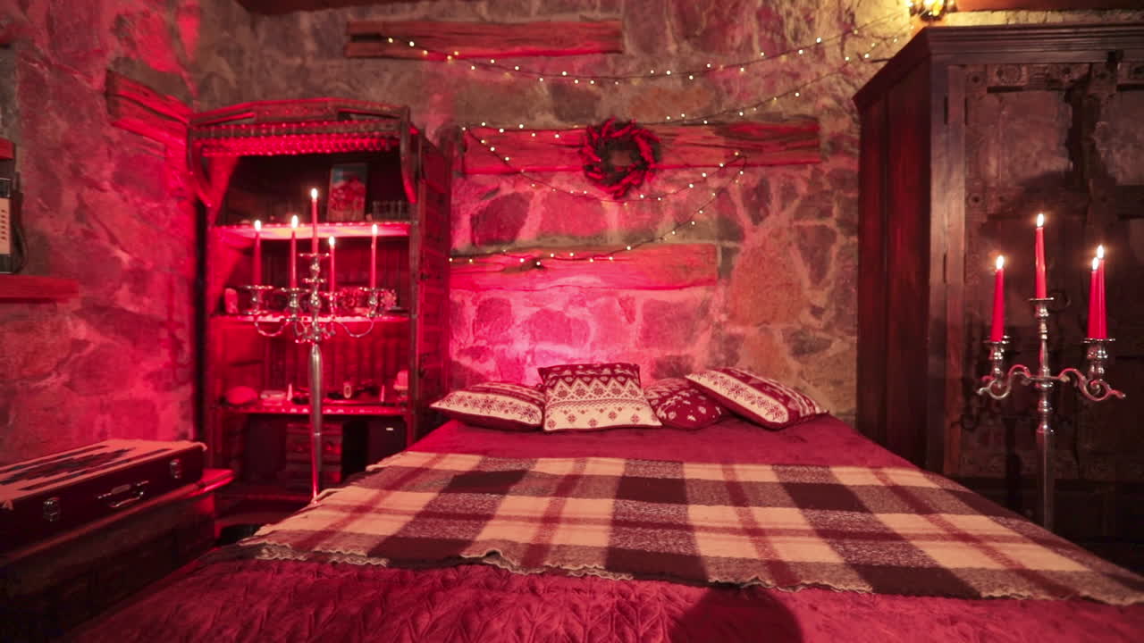 Old-fashioned style bedroom in private manor outside the city. Festively decorated cozy room in castle-like manner lit in red light.