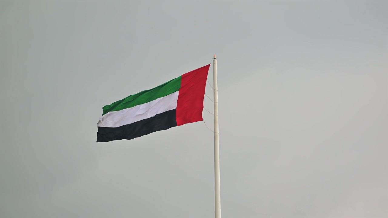 The UAE flag waves gracefully in the air in a close-up shot.