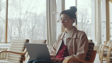 Mujer-Joven-Que-Trabaja-En-La-Computadora-Portátil-En-El-Auditorio-De-La-Biblioteca