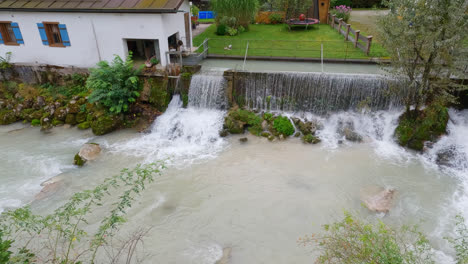 Pan-across-water-spilling-over-dam-into-river-in-Bavarian-foothills