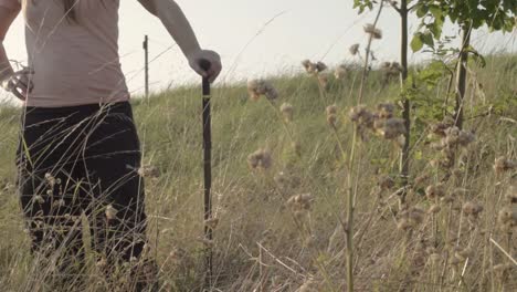 Woman-standing-with-walking-stick-in-countryside