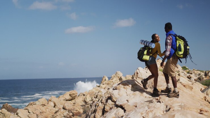 Couple afro-américain grimpant sur les rochers pendant une randonnée