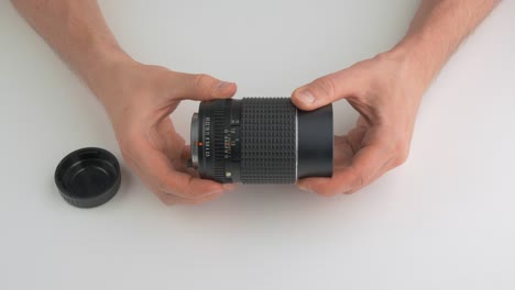 man rotating the aperture ring of a camera lens