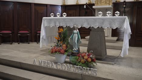 altar de la iglesia decorado con una estatua de la virgen maría y vibrantes arreglos florales