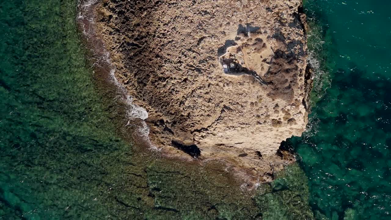 Aerial view of a rocky islet surrounded by clear turquoise waters in Crete Greece