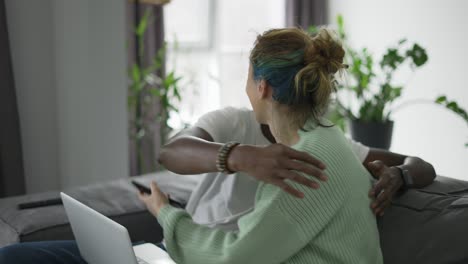 Feliz-Pareja-Birracial-Sentada-En-El-Sofá-Con-Una-Computadora-Portátil-Y-Un-Teléfono-Celular,-Felicitándose-Unos-A-Otros