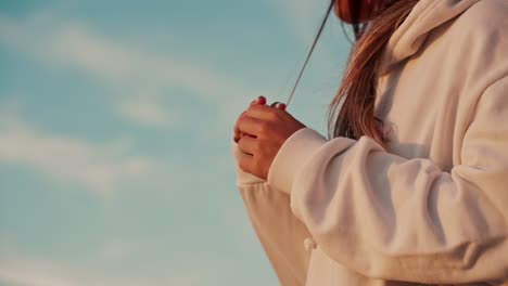 slow motion shot of a girl playing with the ends of her hair whilst watching the sunset