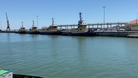 zoom in to some armed forces ships on the river with some sportsmen doing canoeing, alcântara, portugal