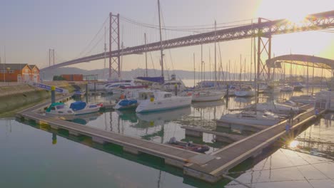 una hermosa vista majestuosa del puerto con pequeños botes bajo el puente abril al atardecer, lisboa, portugal