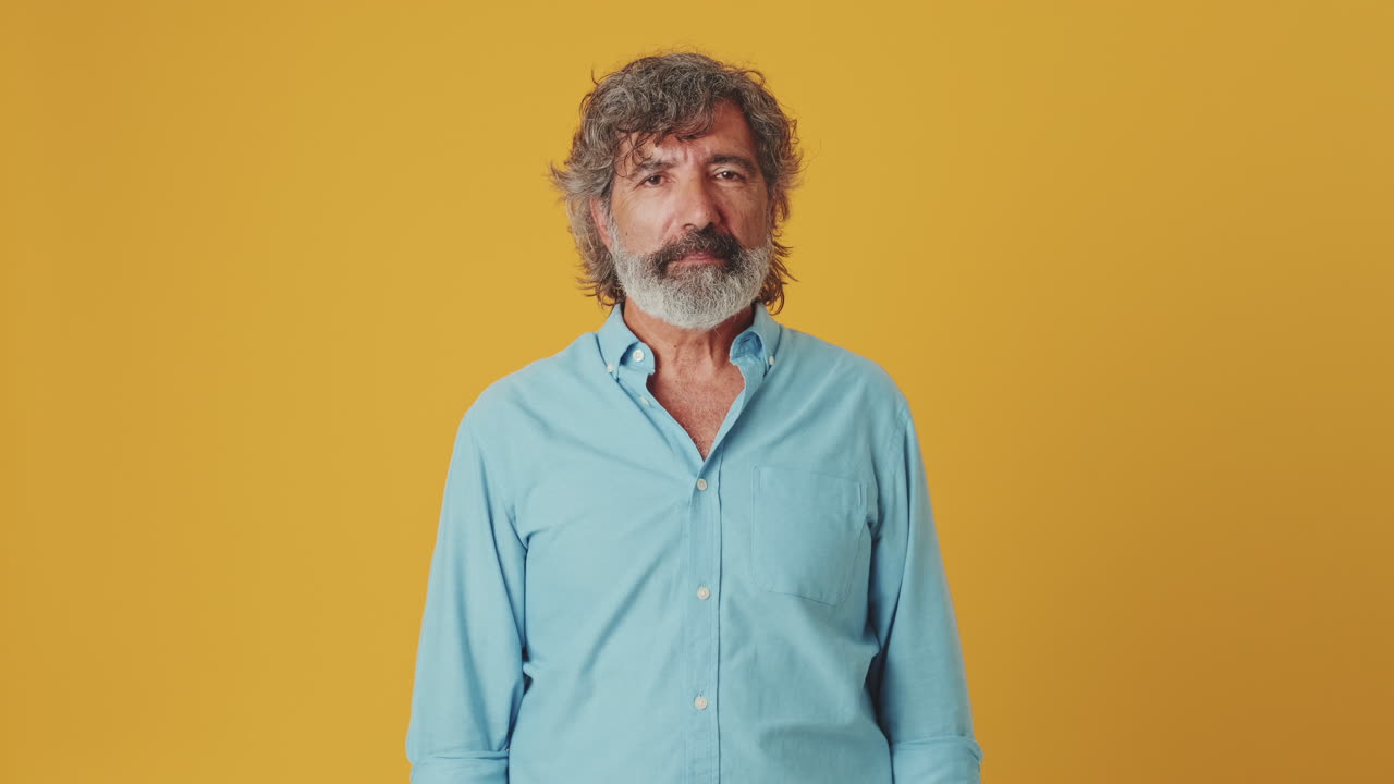 Portrait of a middle-aged man with a beard on a yellow background