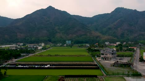 Rolling-drone-shot-view-of-the-beautiful,-green,-lustful-mountain-with-a-farm-base