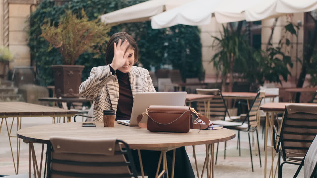 mujer de negocios trabajando en una computadora portátil en un café al aire libre.