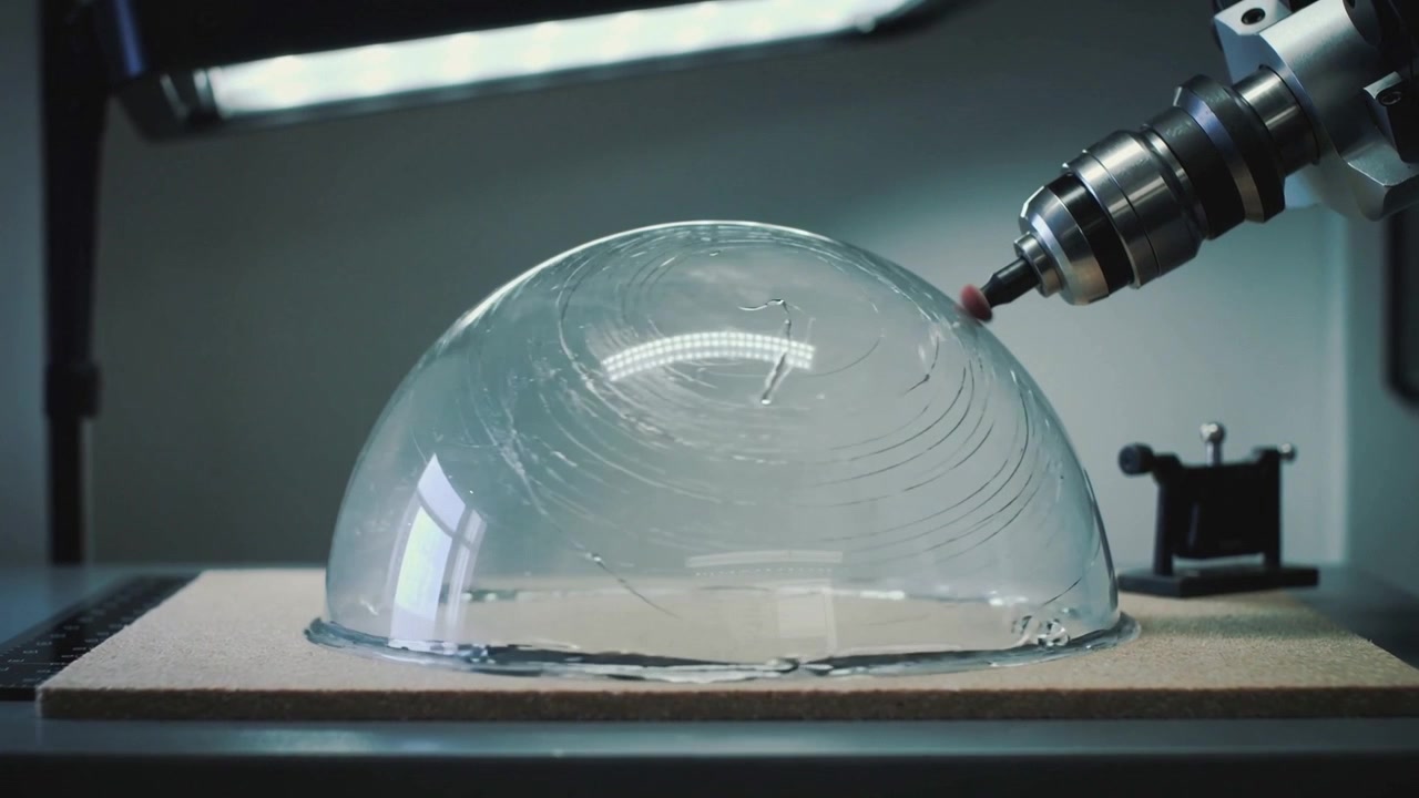 Un utensile rotante da banco per la molatura tocca una cupola su una tavola di legno in un'officina, testandone la durabilità.