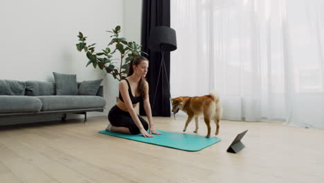 Eine-Sehr-Süße-Junge-Frau-Macht-Zu-Hause-Yoga,-Während-Ihr-Hund-Immer-Wieder-Um-Sie-Herum-Kreist