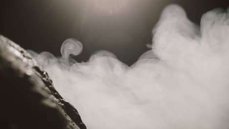 close up view of rocks in the thick smoke on a dark background. slow motion