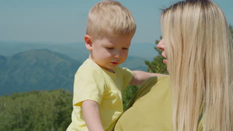 pretty mother cuddles little son against distant mountains