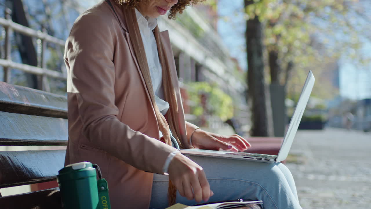 Businesswoman Working on Laptop and Making Notes on Street Bench