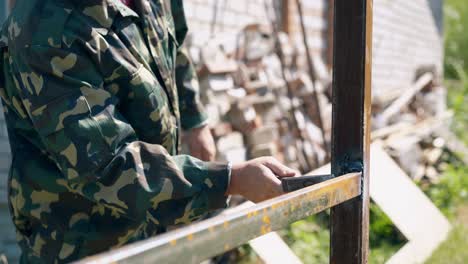 closeup-craftsman-taps-on-welded-fence-parts-with-hammer