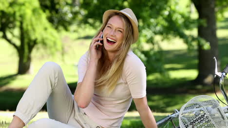 pretty girl talking on smartphone beside her bike in the park