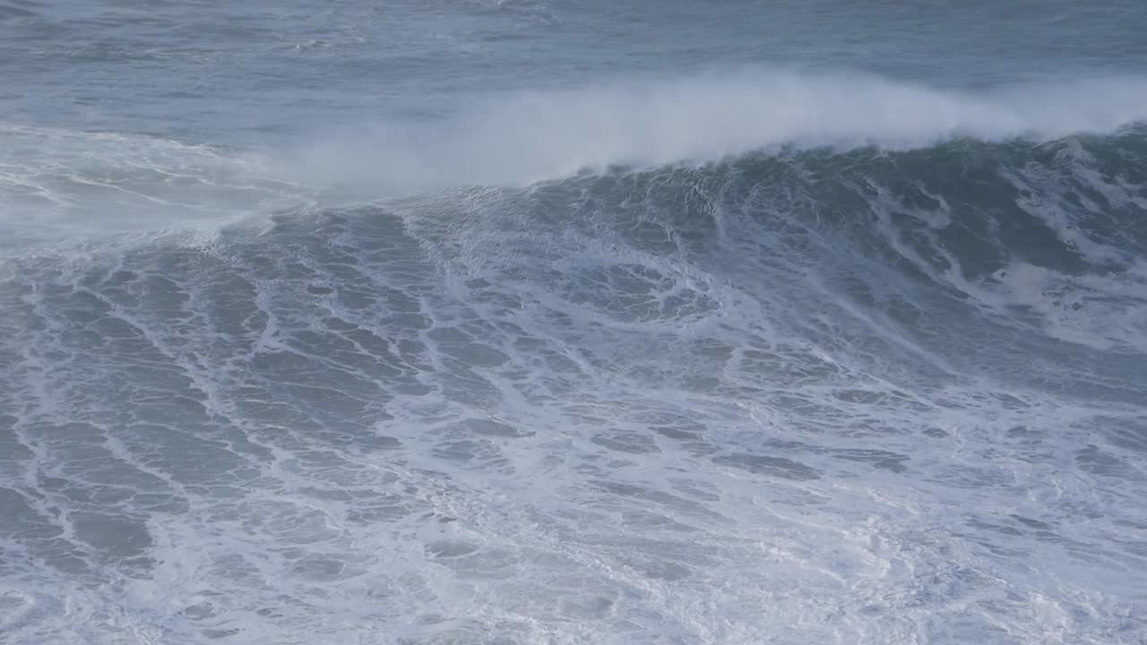 Huge waves crashing at Nazaré beach, Portugal, creating a dramatic seascape