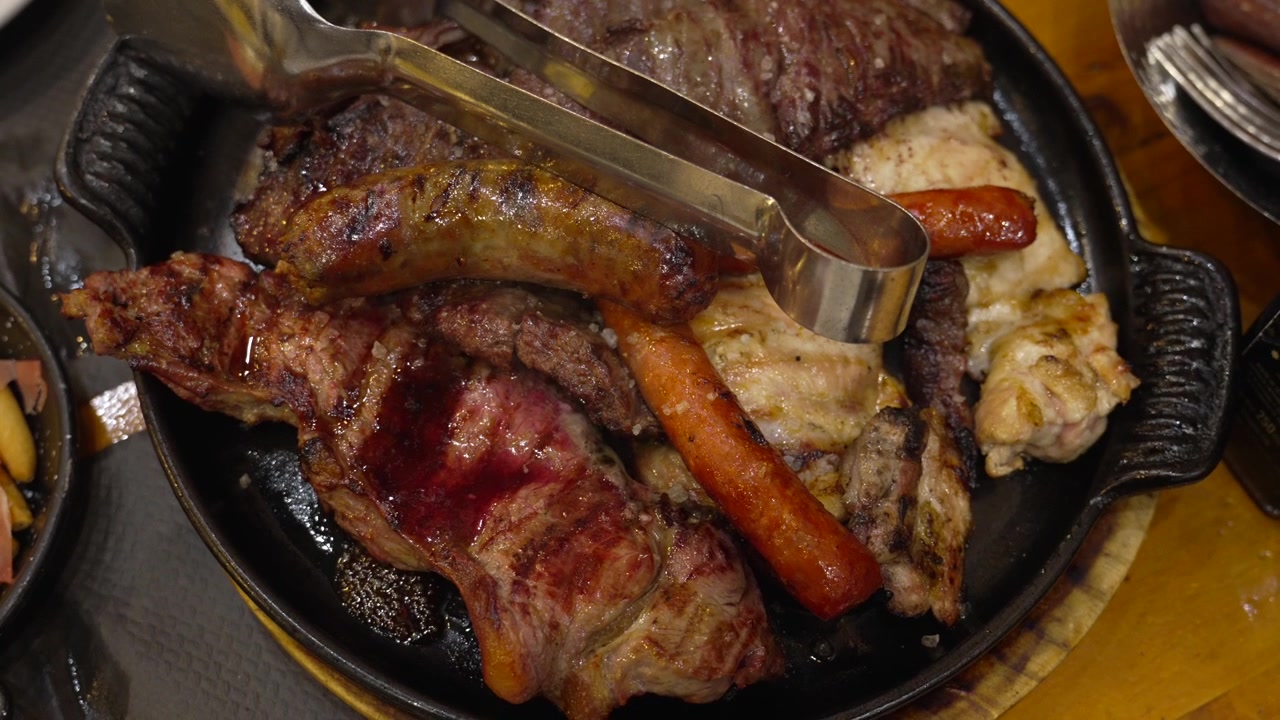 Travessa de carne gourmet chiante com bifes grelhados, linguiças saborosas e vários cortes de aves, apresentando uma farta experiência de jantar espanhol em Madrid.