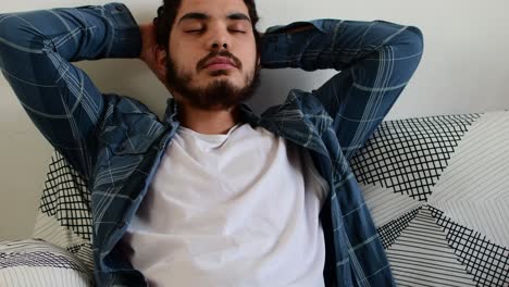 young man accommodates himself to rest on the sofa in the living room of his home.