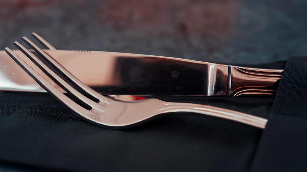 Close up of silver cutlery placed neatly on a dark napkin at a restaurant