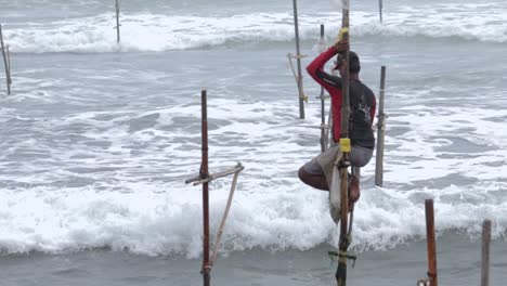 isolated lonely stilt fisherman with a cap and bag ready for his job at the weligama beach, empty stilts all around him