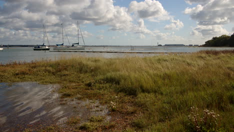 wide shot of low lying grass flooded at high tide taken at ashlett creek sailing club in the solent, southampton