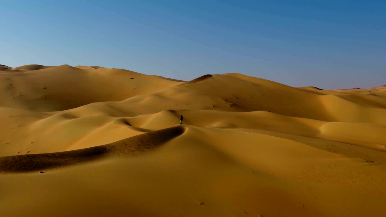 vista aérea de un hombre de pie en el borde de las dunas, u.a.e.