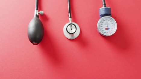 video of stethoscope with sphygmomanometer on red background with copy space