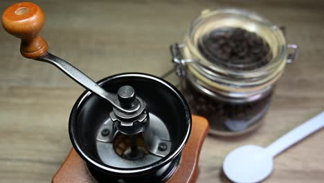 a zoom out of an ensemble coffee grinder, jar with coffee beans, spoon, on the table