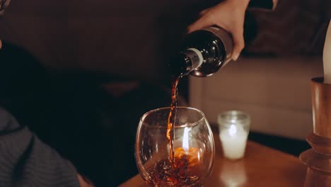 Pouring-red-wine-in-glass-on-romantic-dinner-table-with-candles,-close-up,-slow-motion