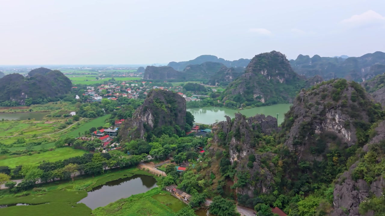 Cảnh quay điện ảnh từ trên cao về những khối núi đá vôi cao chót vót vươn lên trên sông, vùng nông thôn và làng mạc ở miền Bắc Việt Nam.