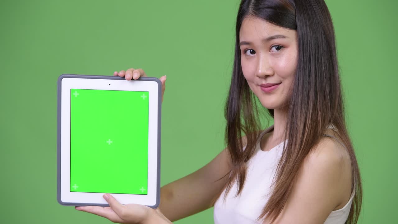 젊은 아름다운 아시아 사업가 여성이 디지털 태블릿을 보여줍니다.