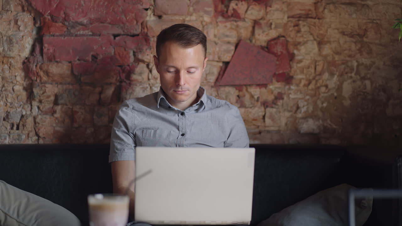 hermoso desarrollador masculino o estudiante trabajando estudiando con computadora portátil en una cafetería. trabajo remoto independiente educación en línea autónomo