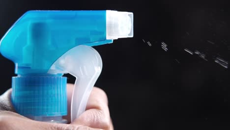 close-up of a hand holding a blue spray bottle