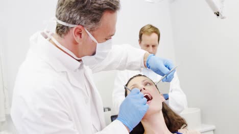 dentist examining a female patient with tools