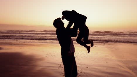 puesta de sol, playa y papá girando niño en silueta