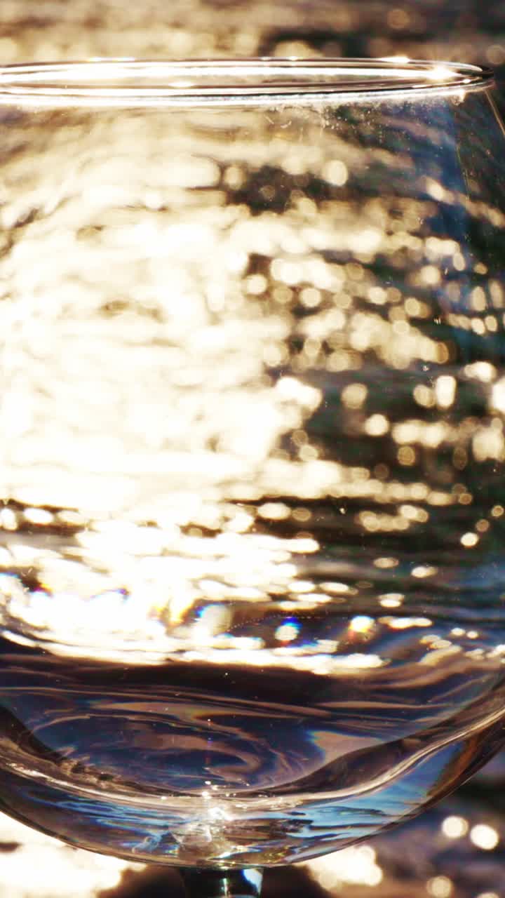 Vista astratta dell'acqua in un bicchiere con luce dorata scintillante