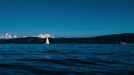 Vista-En-ángulo-Bajo-Y-Cámara-Lenta-De-Color-Azul-Verde-Azulado-De-Un-Pequeño-Bote-Navegando-En-Las-Tranquilas-Aguas-Abiertas-Del-Lago-Maggiore-En-Italia