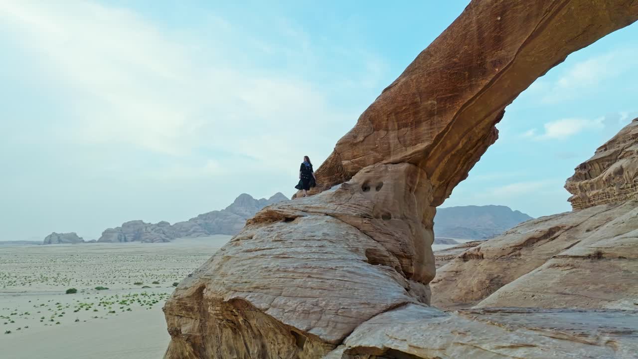 turista femenina en el arco natural de al kharaza en el desierto de wadi rum en aqaba, jordania