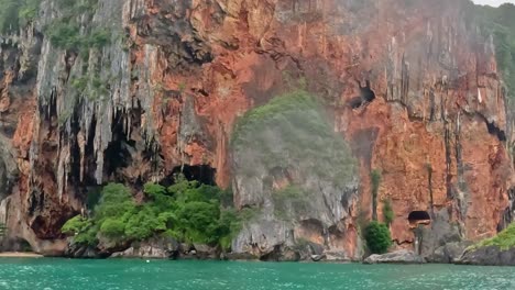 explore the vibrant limestone cliffs adorned with lush greenery against a serene turquoise sea.