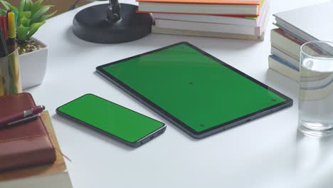 green screen tablet and phone on a desk with books