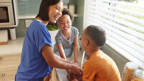 mother washing vegetables with children in kitchen, enjoying african american family time together